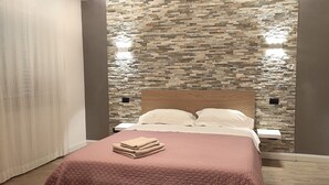 Een slaapkamer met een stenen muur, een houten hoofdbord en een roze sprei.