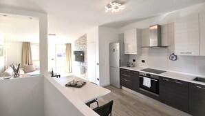 Een moderne keuken met een ingebouwde oven, een groot kookeiland met zitplaatsen en een eethoek.