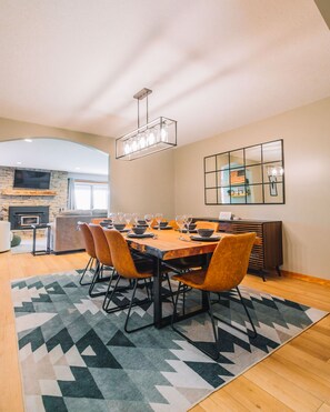 A dining area with a wooden table set for six, surrounded by six chairs.
