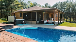Une maison avec une piscine, du mobilier d’extérieur et un patio couvert.