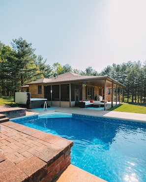 Ein Haus mit Pool, Gartenmöbeln und einer überdachten Terrasse.