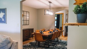 Un coin repas avec une table en bois dressée pour six personnes, entourée de chaises, et un tapis à motifs sur le sol.