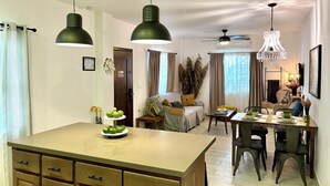 A modern kitchen with a central island, pendant lighting, and a dining area with a chandelier. - Stylish Apartments in Belize City (Belize City)