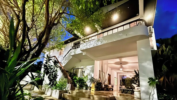 A modern building with a spacious outdoor area, a staircase, and various potted plants. - Stylish Apartments in Belize City (Belize City)
