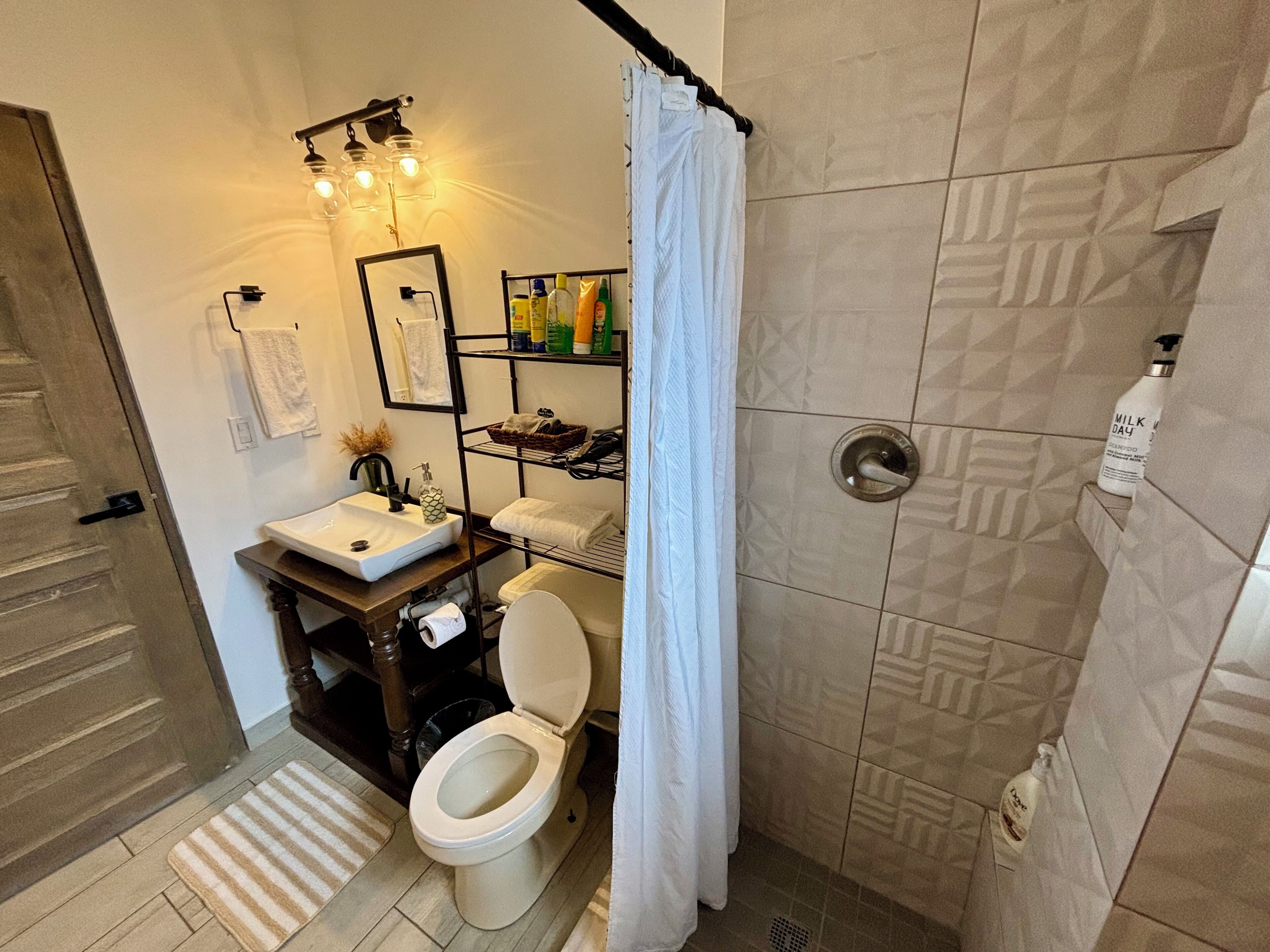 A bathroom with a sink, toilet, and shower area.