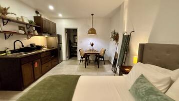 Habitación de hotel compacta con kitchenette, comedor y cama.