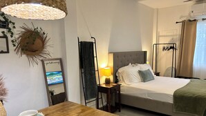 A neatly arranged hotel room with a bed, bedside table, lamp, and a television on the wall. - Stylish Apartments in Belize City (Belize City)
