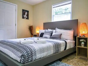 A neatly made bed with a geometric patterned bedspread, a headboard, and two bedside lamps. - Picture Perfect Paradise 3br / 3ba (Orange Park)