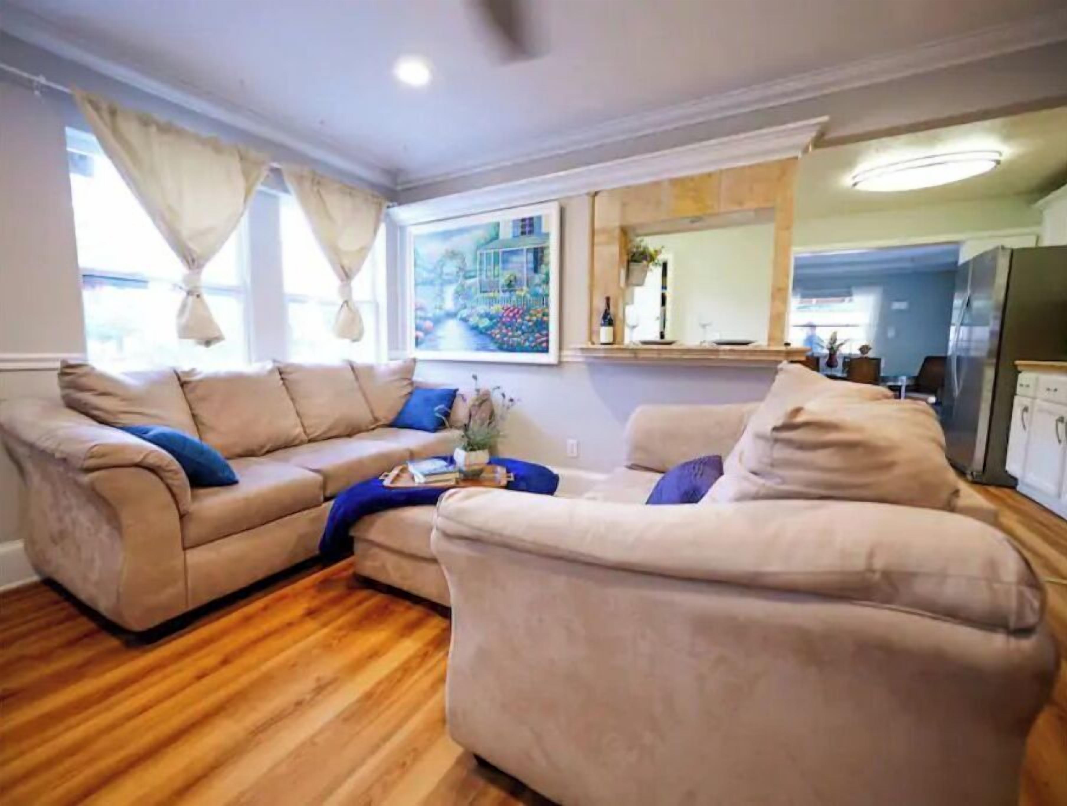 A living room with two beige sofas, a coffee table, and a wooden floor.