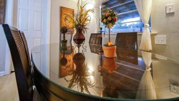Un coin repas avec une table en verre, des chaises et une plante en pot.