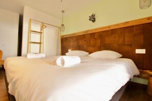 A neatly made bed with white linens and a rolled towel, a wooden headboard, a wall-mounted light fixture, and a small decorative item above the headboard. - Le M, 120m2 apartment, right in the center. (Font-Romeu-Odeillo-Via)