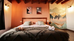 A bedroom with a wooden ceiling, a bed with rolled towels, two wall-mounted lamps, and a mountain landscape mural. - Duplex M, huge loft in resort center (Font-Romeu-Odeillo-Via)