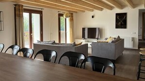 A modern living room with a wooden ceiling, a flat-screen TV, a sofa, and a dining area with chairs. - Duplex M, huge loft in resort center (Font-Romeu-Odeillo-Via)