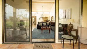 A modern home interior with a living room, kitchen, and dining area visible through glass doors. - Palm Desert Private Retreat  (Palm Desert)
