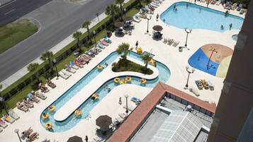 Relax by the winding pool, surrounded by lounge chairs and umbrellas, with a panoramic view of the surrounding area.