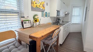 A compact kitchen with a wooden table, two chairs, a vase with sunflowers, a Wi-Fi sign, and a street guide on the wall. - Cozy Private Share Room (Englewood)