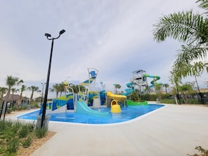 Parque acuático con varias toboganes y piscinas, rodeado de palmeras y un cielo despejado.