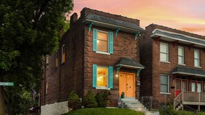A two-story brick house with a front porch, a small front yard, and a street sign indicating 'SIDNEY ST.' - Soulard Retreat. Fire Pit. Game Room. 3 Kings (St. Louis)