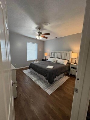 A bedroom with a bed, nightstands, a ceiling fan, and a window.