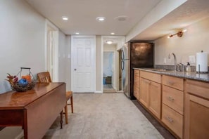 A kitchen with wooden cabinets, a countertop, and a refrigerator.
