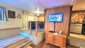 A hotel lobby with a wooden staircase, a reception desk, a television mounted on the wall, and a patterned wall design. - This fourplex is a 1 bedroom(s), 1 bathrooms, located in Shaver Lake, CA. (Shaver Lake)
