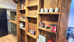 A kitchen with wooden shelves holding various kitchen items and a black stove. - This fourplex is a 1 bedroom(s), 1 bathrooms, located in Shaver Lake, CA. (Shaver Lake)