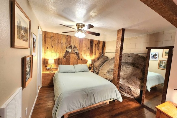 This unique bedroom includes a queen size bed, closet, and full size mirror. the bedroom area sits underground and has a huge granite rock coming out of the side of the wall! Linens and extra blankets are included in your stay.