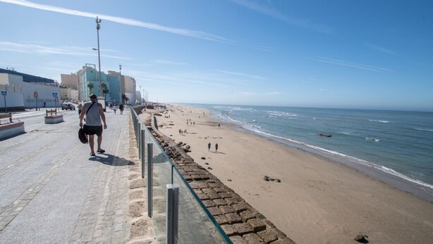 A coastal promenade with a stone barrier, beach, and buildings in the background. - Apartment Tribalia - Cadiz beaches (Cádiz)