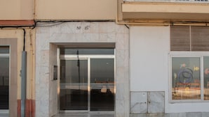 A building facade with a numbered entrance, a glass door, and a window with colorful artwork. - Apartment Tribalia - Cadiz beaches (Cádiz)