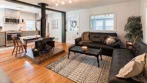 A modern living room with a fireplace, a sofa, a coffee table, and a dining area with a table and chairs.