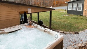 A hot tub with a wooden deck and a covered seating area.