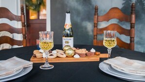 A table set with two glasses of white wine, a bottle of wine, and a variety of snacks.