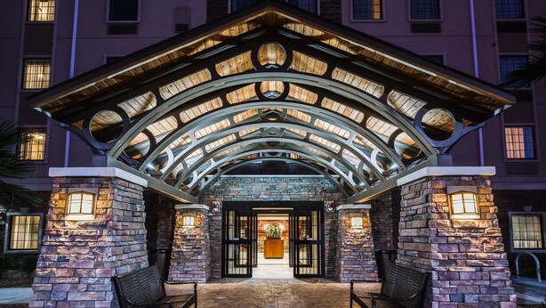 A hotel entrance with a stone facade, arched roof, and illuminated windows. - 2 Bedrooms | Free Daily Breakfast, Outdoor Pool (El Paso)