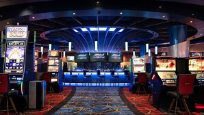 A casino interior with slot machines, a bar area, and a patterned carpet.