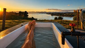 A bathtub with a view of a lake and mountains during sunset. - Coastal Calm | Luxe Stay with Views, Bath & Fire. (Mapua)