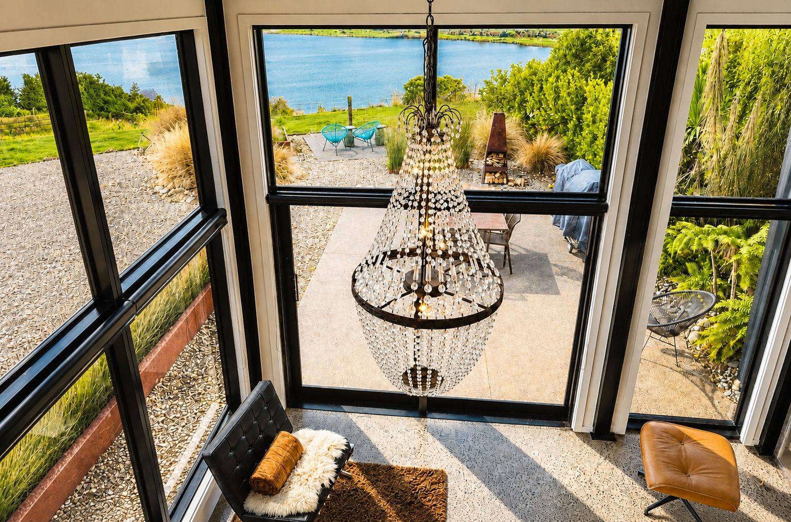 Una habitación con un amplio ventanal que da a un jardín y un lago.