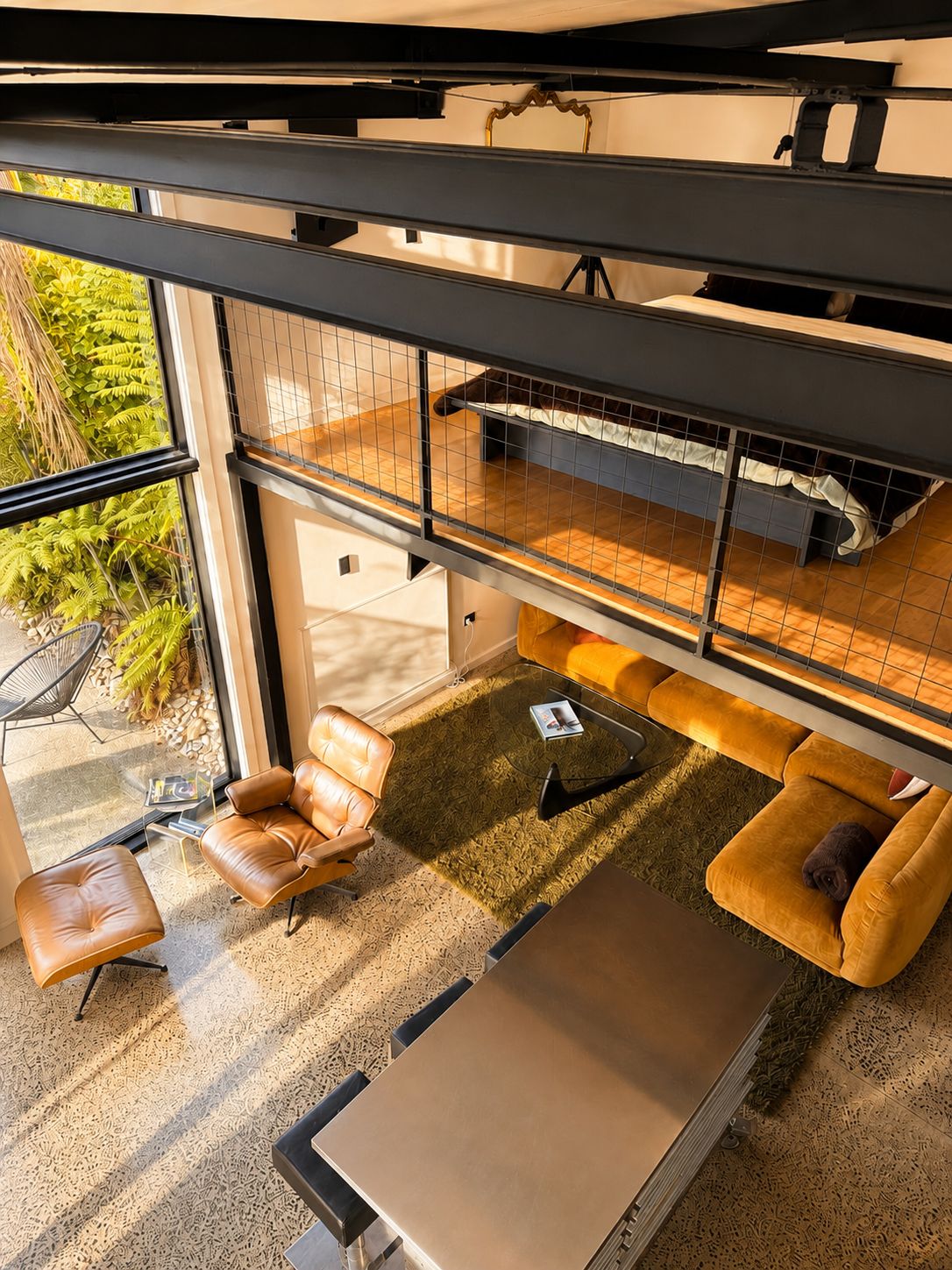 Un intérieur moderne avec une pièce aux murs de verre, des meubles en cuir et un jardin extérieur visible.