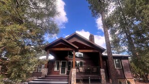 A wooden cabin with a stone foundation, a front porch, and a staircase leading to the entrance.