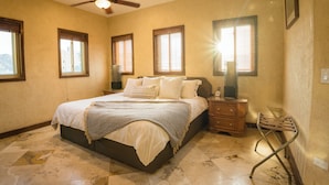 A bedroom with a bed, nightstands, a ceiling fan, and a window with blinds. - Secluded Cabo Hideaway! Walk to the beach, ample space,  pool and rooftop deck! (Cabo San Lucas)