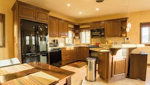A kitchen with wooden cabinets, a stainless steel refrigerator, a stove, and a sink. - Secluded Cabo Hideaway! Walk to the beach, ample space,  pool and rooftop deck! (Cabo San Lucas)