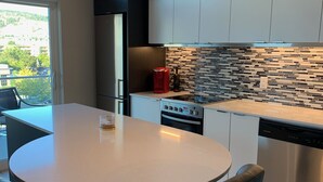 Une cuisine moderne avec une table de salle à manger ronde, des chaises noires et un luminaire suspendu.