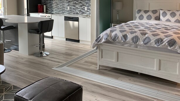 Une chambre moderne avec un grand lit, une petite kitchenette et un coin repas équipé d’un tabouret de bar.