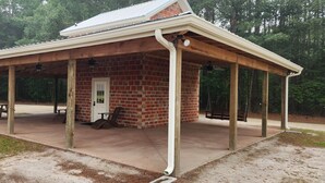 A covered pavilion with a brick exterior, a door, and a picnic table.