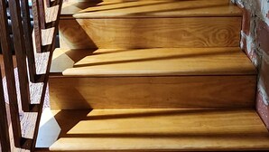 A wooden staircase with a metal railing, leading to a brick wall.