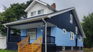 A two-story house with a blue exterior and a wooden front porch.