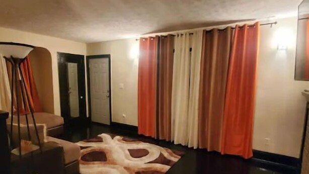 A room with a dark wooden floor, a patterned rug, and a door.