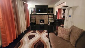 A living room with a fireplace, a sofa, a TV, and a lamp.