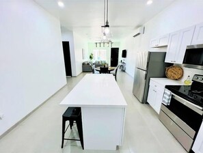 Enjoy cooking in this well-equipped kitchen with a central island, stainless steel appliances, and white cabinetry.