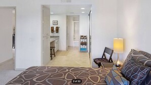 Hotelkamer met een bed, een bureau, een stoel, een lamp en uitzicht op de keuken en badkamer.