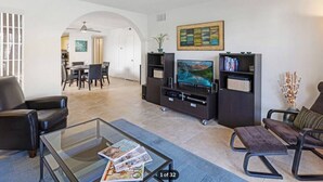 Een moderne woonkamer met een glazen salontafel, een leren bank en een entertainmentsmeubel met een flatscreen televisie.